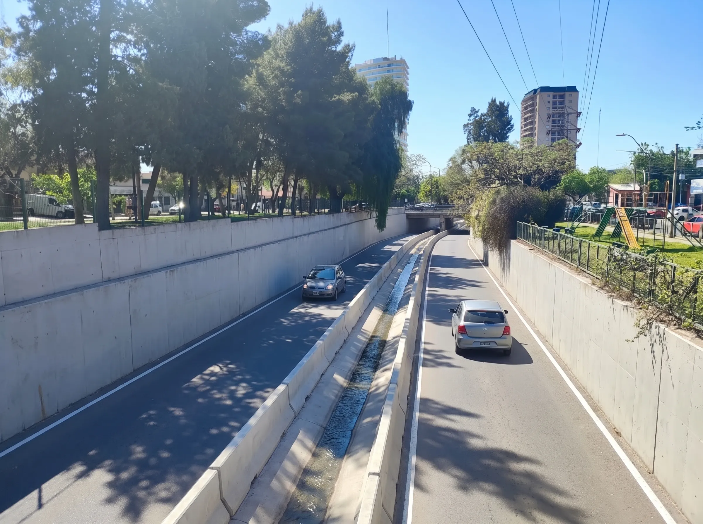 La propuesta vista hacia el este: la vía pasa por debajo del puente, con el canal central y dos autos